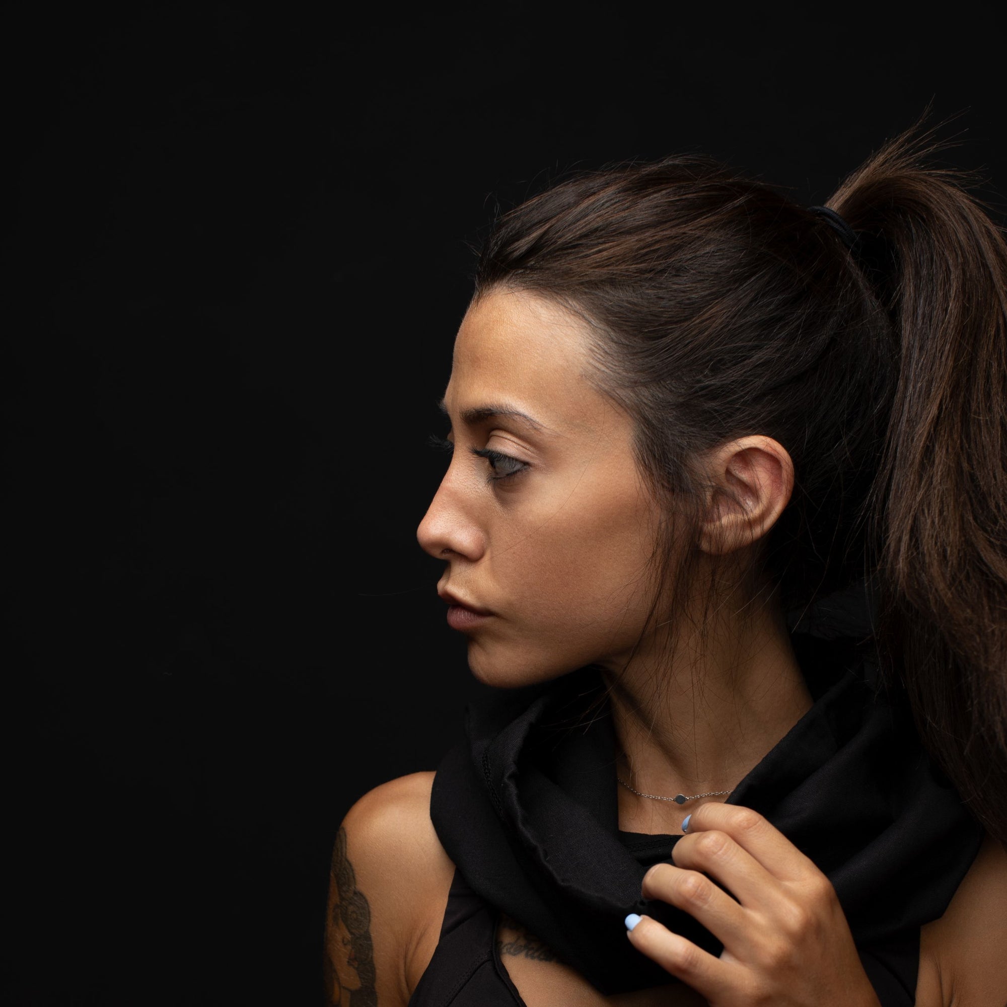 Young woman profile looking to the side with a black hemp and cotton biogaiter around her neck