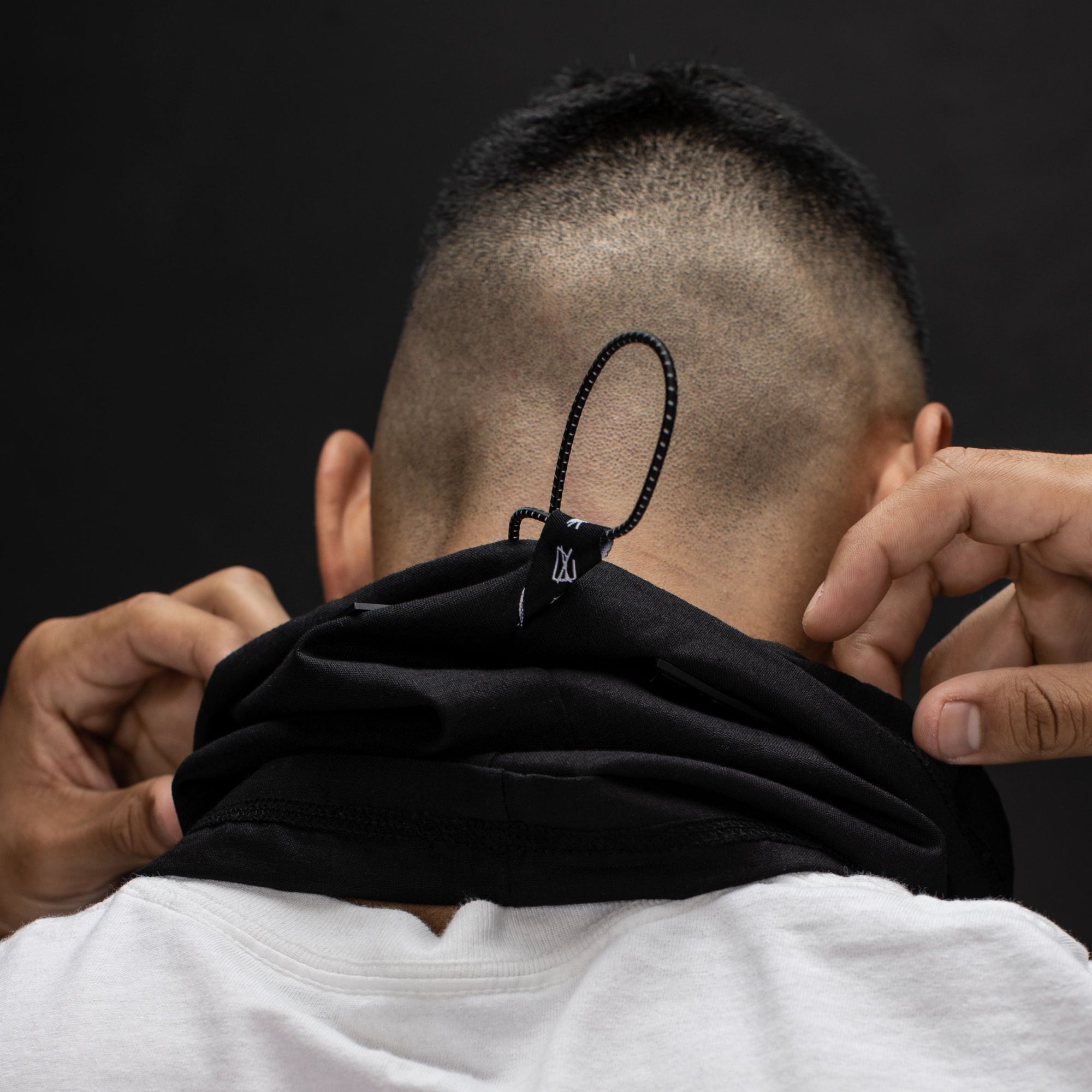 Young man with short hair turned around with a black hemp and cotton biogaiter around his neck